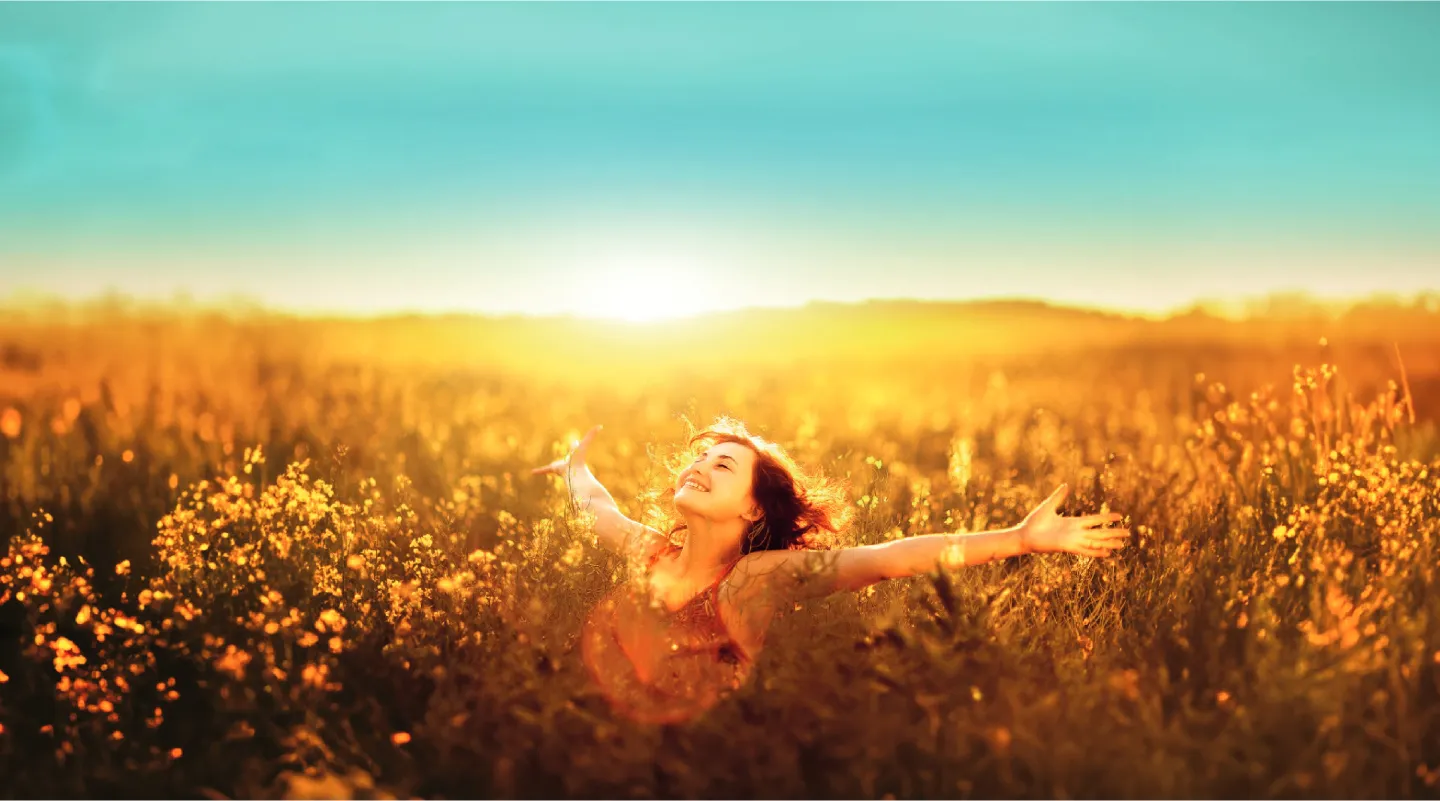 Vrouw in een veld met bloemen en de warme zon
